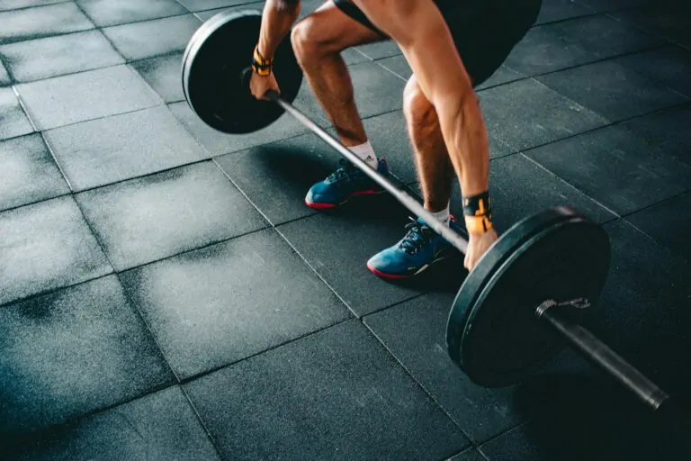 bodybuilder using lifting straps barbell row